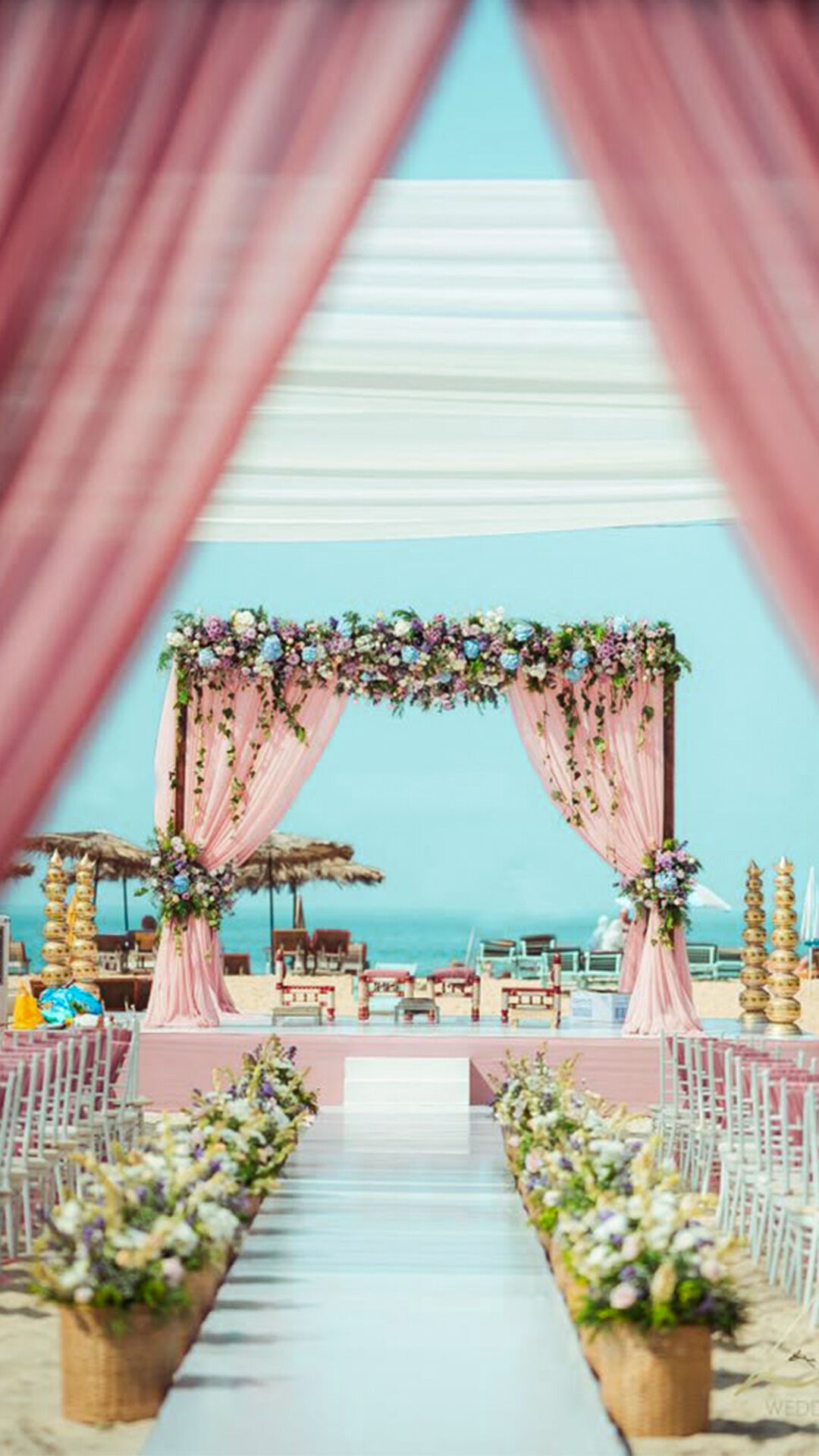 Romantic beach wedding setup adorned with colorful floral arrangements.